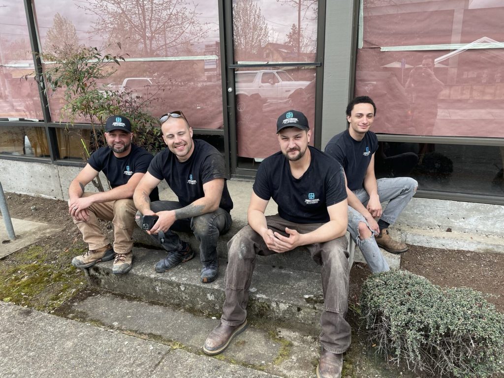 Four Precision Plumbing crew members in branded shirts on a job site