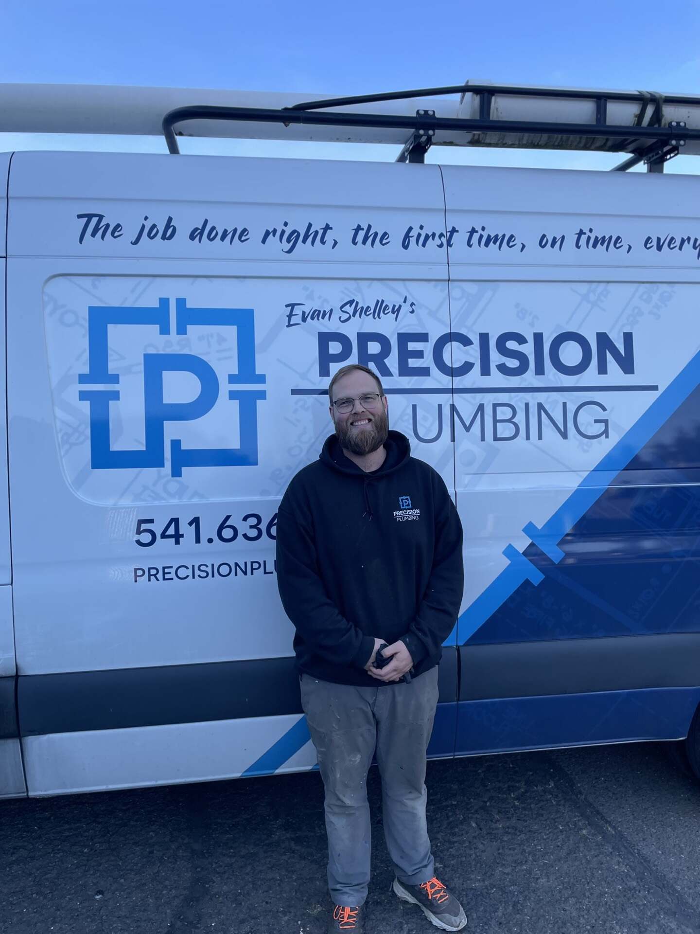 Precision Plumbing technician standing in front of a branded company van