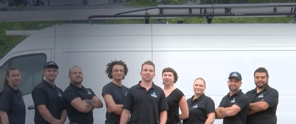 The Precision Plumbing team standing together in front of a white Precision Plumbing service van