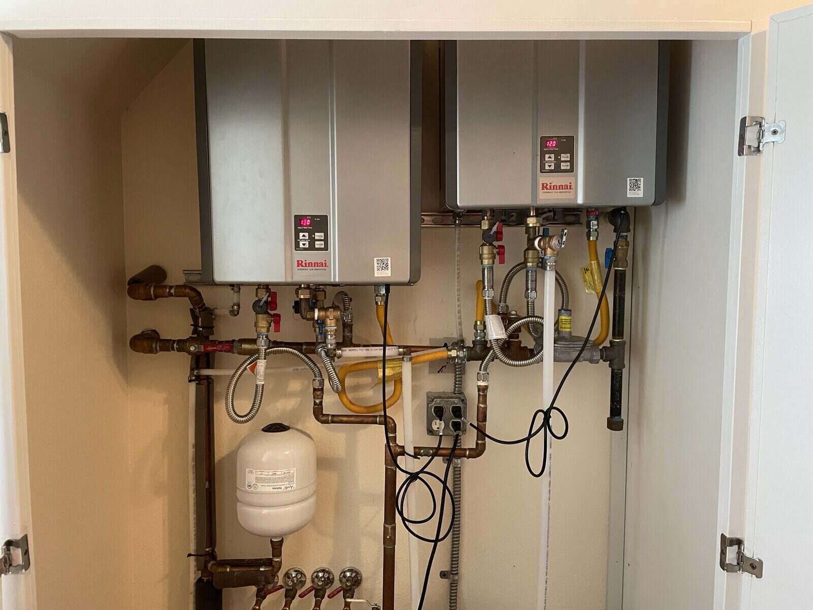 Two wall-mounted tankless water heaters with copper supply connections