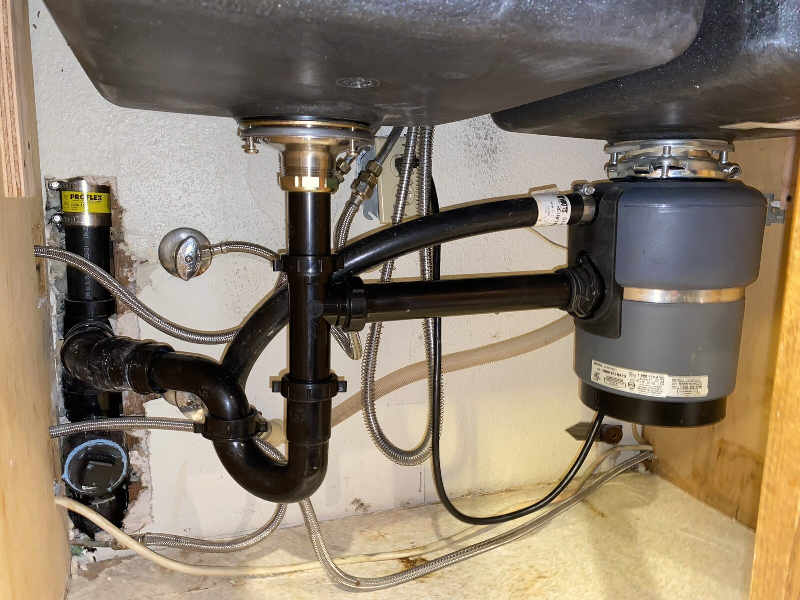 Garbage disposal and P-trap assembly under a kitchen sink