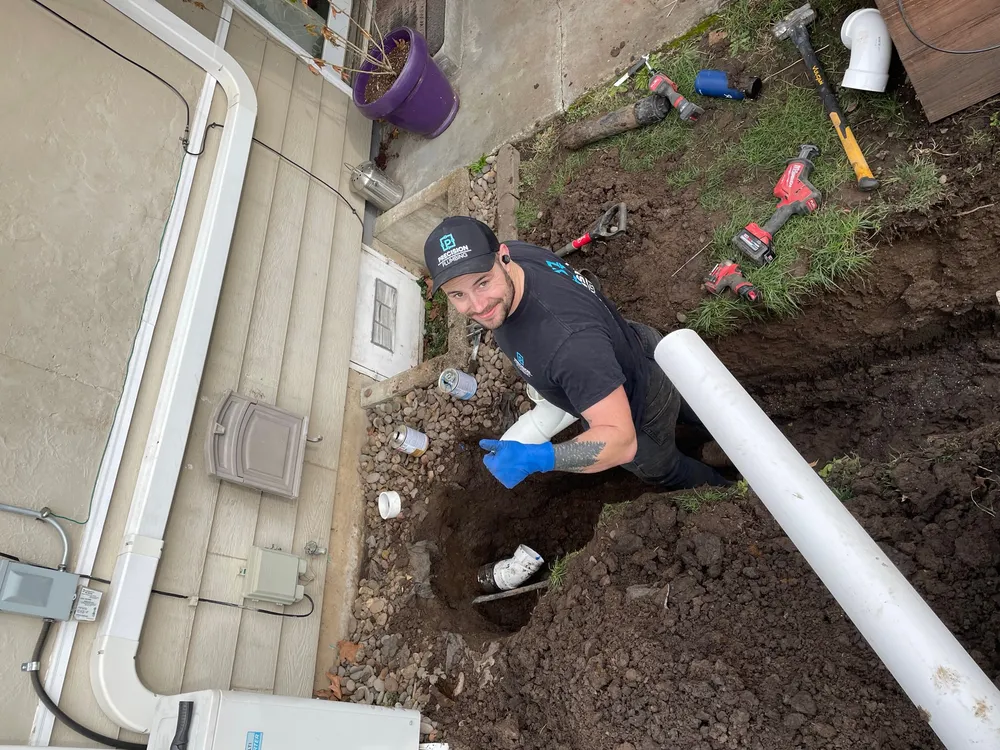 Precision Plumbing technician in a trench beside a house