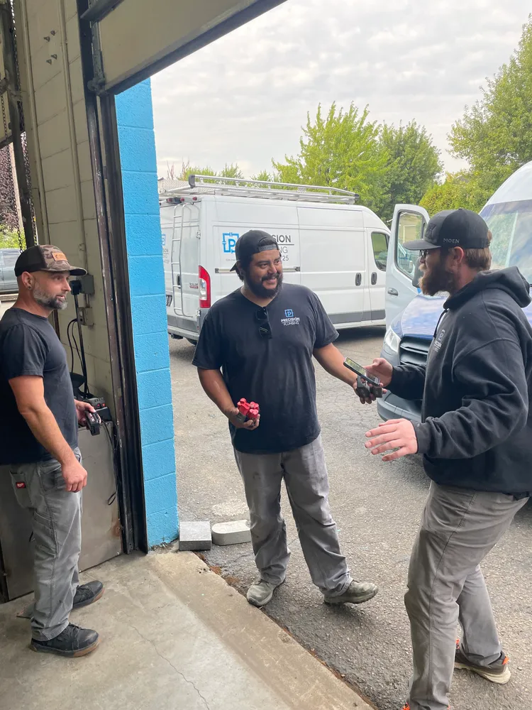 Precision Plumbing crew talking beside the vans