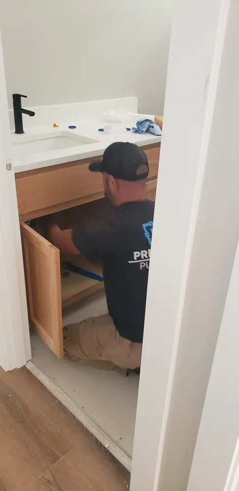 Plumber connecting supply lines under a bathroom vanity