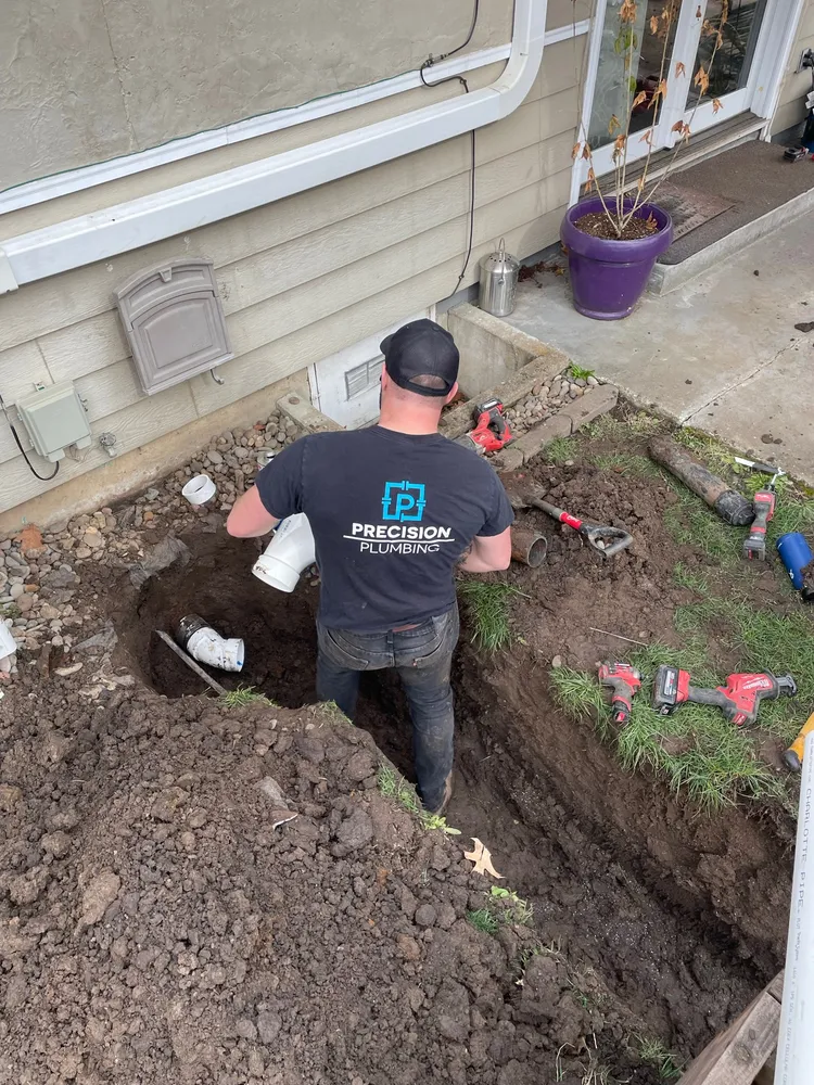 Precision Plumbing technicians digging beside a house