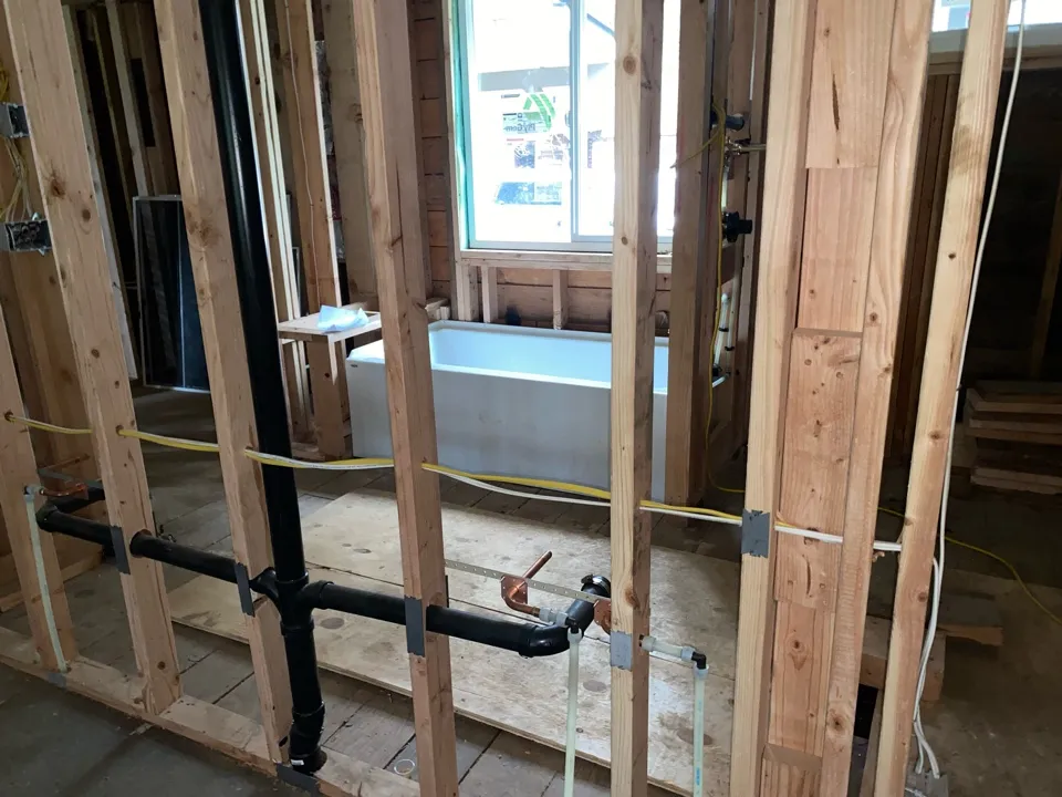 Plumber running pipe through an open wall
