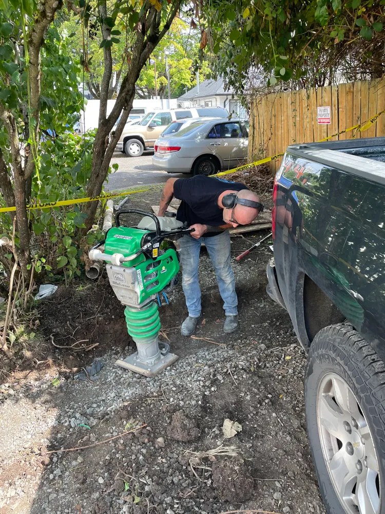 Crew digging out a leaking line beside a home