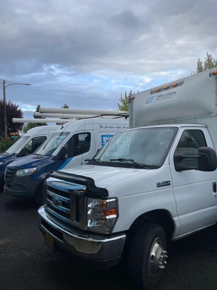 Precision Plumbing vans parked on a job site