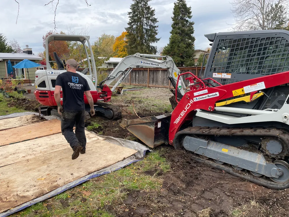 Mini excavator beside a home during a sewer dig