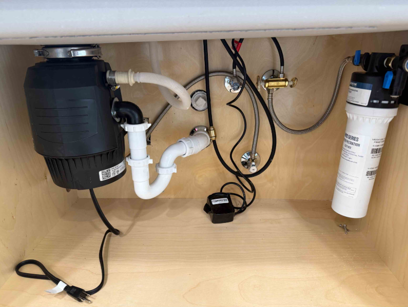Under-sink water filter beside a garbage disposal