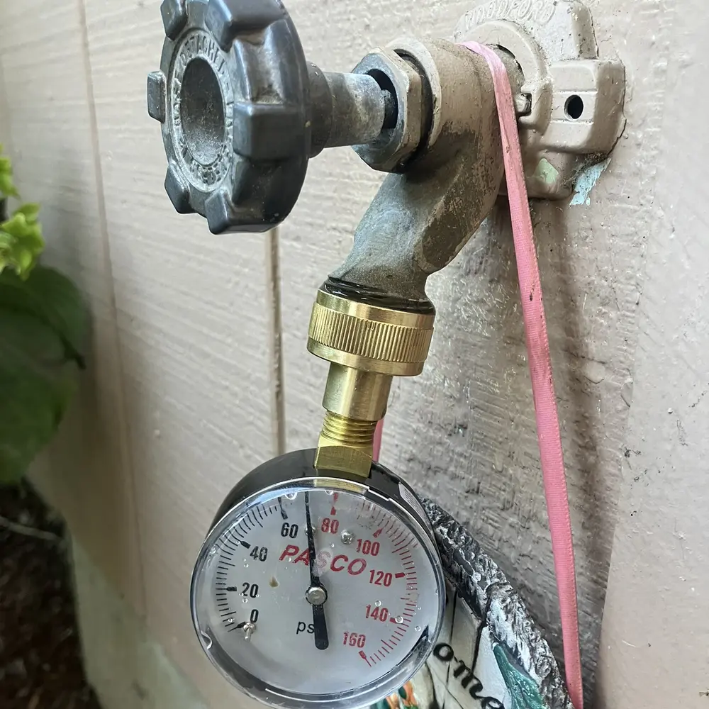 Pressure gauge attached to an outdoor hose bib during a water pressure test